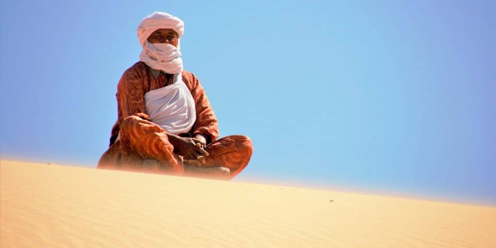 Argelia. Tuareg envuelto en sus ropajes en la cima de una duna del desierto del Sahara cerca de Tassili N'Ajjer en Argelia