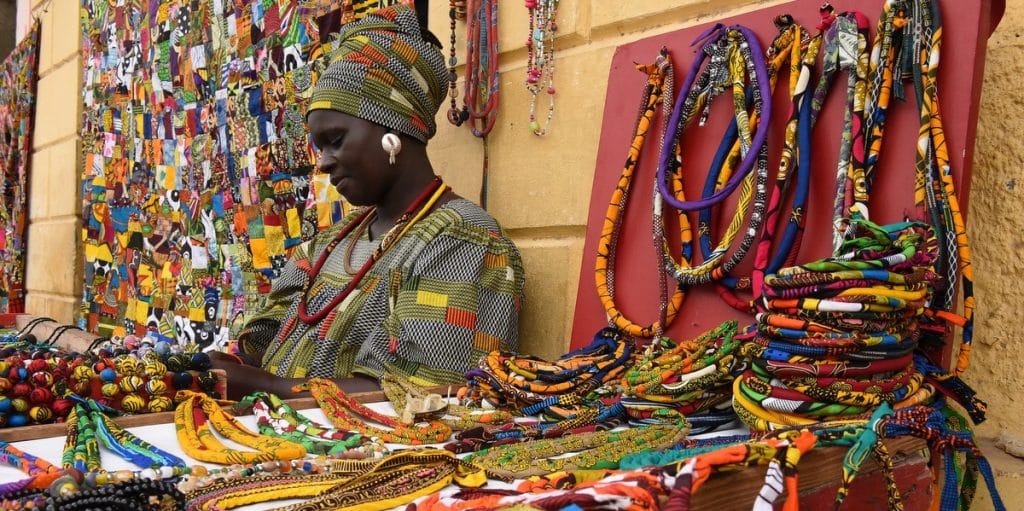 Senegal. Puesto en el mercado de St Louis donde se venden collares realizados con las telas estampadas típicas de la zona y mujer atendiendo el puesto, en Senegal