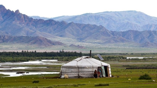 Mongolia. Tienda nómada (Ger) mongola montada en mitad del amplio paisaje, con ríos y mandas de caballos al fondo, en Mongolia